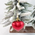 Matte red heart-shaped Christmas ornament with gold string on a snowy pine branch - Red Ball Matte