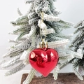 Glossy red heart-shaped ornament with gold string hanging on a snowy Christmas tree - Red Ball Glossy