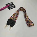 Detail of colorful geometric pattern strap with black leather ends and gold metal clips - Radiant