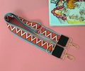 Close-up of bohemian geometric woven bag strap with leather ends and golden metal clips - Iridescent