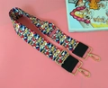 Detail of colorful geometric woven strap with golden metal hooks and black leather - Radiant