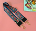 Dettaglio della tracolla etnica ricamata con motivi floreali e fibbie metalliche dorate - Tarassaco