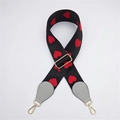 Macro detail of black woven bag strap with red heart embroidery and golden metal buckles - Gray