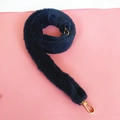 Dettaglio tracolla in finta pelliccia blu navy con moschettoni dorati su fondo rosa - Blu