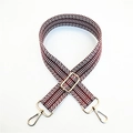 Close-up of ethnic geometric wave pattern on red and white woven bag strap with gold buckle - Brown