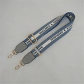 Detail of adjustable grey-blue fabric shoulder strap with gold metal hooks and logo webbing - Gray