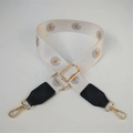 Detail of adjustable canvas bag strap with daisy floral print and gold lobster clasps - White/Orange Flower With Black Leather