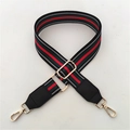 Detail eines verstellbaren rot-grün gestreiften Taschenriemens mit goldenen Metallhaken - Schwarz
