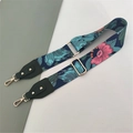 Detail eines geblümten Taschenriemens in Marineblau mit goldenen Metallschnallen - Blaues Blumenmuster + Grünes Leder