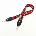 Detail eines verstellbaren Taschenriemens mit Leopardenmuster, Goldschnallen und Lederenden - Rot