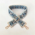 Close-up of ethnic geometric woven purse strap with golden metal swivel hooks and adjuster - Light Blue Floral Pattern