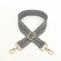Detail of adjustable black and white chevron patterned woven shoulder strap with gold clips - Black