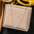 Elegant silver-colored triple heart pendant necklace on a beige jewelry display box - Triple Heart Necklace Steel (XLH86)