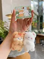 Detail of plush cat couple charms with orange stripes and white fur on a green card - Cat