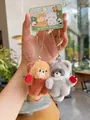 Close-up of plush panda and raccoon keychains with red hearts and magnetic attraction - Raccoon