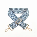 Macro view of blue and white geometric jacquard strap with gold-tone metal hardware - Blue
