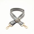 Close-up of adjustable grey nylon bag strap with white V-pattern and gold metal buckles - Gray