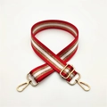 Détail d'une bandoulière rayée rouge et blanc avec mousquetons et boucle en métal doré - Rouge