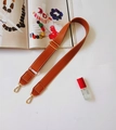 Detail view of brown PU leather shoulder strap with golden metal buckle and white stitching - Brown