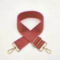 Close-up of woven geometric bag strap in magenta and yellow with gold-tone metal hooks - Pink