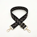 Close-up of adjustable woven purse strap with black grey geometric pattern and gold hardware - Dark Gray