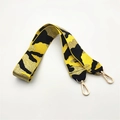 Detail eines gelb-schwarzen Taschenriemens mit goldenen Fäden und Metallkarabinern - Camouflage Gelb