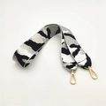 Detail eines breiten Stoff-Taschenriemens mit schwarz-weißer Textur und Goldkarabinern - Camo Weiß