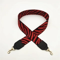Detail of red and black zebra pattern wide fabric shoulder strap with gold metal hooks - Red Black Stripes + Black Leather