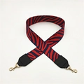 Close-up of red and blue zebra striped fabric bag strap with gold metal lobster clasps - Red Blue Stripes + Black Leather