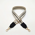 Close-up of adjustable cream webbing strap with black heart patterns and gold hardware - White Black Line + Black Leather / Silver Clasp