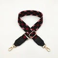 Detail of adjustable bag strap with red and pink star pattern and gold metal lobster clasps - Dark Wine Red with Black Leather