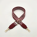 Detail of adjustable woven bag strap with wine red V-pattern and gold hardware - Burgundy