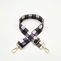 Detail of adjustable plaid bag strap with black, white, and pink weave and gold metal hooks - Gray