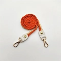 Close-up of woven orange and beige shoulder strap with gold metallic thread and lobster clasps - Orange