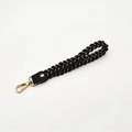 Detailed shot of black and gold woven wrist strap with lobster clasp and leather connector - Black