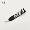 Detailed view of zebra print wrist strap with black leather and golden metal clasp - Silver Clasp / White Zebra Print