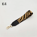 Close-up of zebra pattern woven bag strap with black leather ends and gold metal lobster clasp - Silver Clasp / Khaki Zebra
