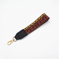 Close-up of ethnic woven wrist strap with geometric patterns and golden metal hook - No.11 Coffee Weave + Black Leather