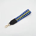 Detailed view of geometric woven strap with black leather trim and gold swivel hook - No.10 Blue Yellow Weave + Black Leather