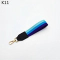 Detail view of tri-color striped handbag wrist strap with golden lobster clasp and black leather - Blue Purple Stripe