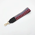 Detailed macro view of woven checkered purse strap with gold lobster clasp and leather trim - No.8 Gray Red Weave + Black Leather / Silver Clasp
