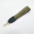 Close-up of retro woven wrist strap with green geometric patterns and gold metal clasp - No.4 Green Weave + Green Leather / Silver Clasp