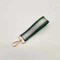 Detail of green and silver striped woven wrist strap with a gold metal lobster clasp - Green