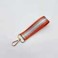 Close-up of orange woven wrist strap with silver reflective strip and gold lobster clasp - Silver Clasp / Orange