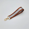 Detail of orange and silver striped wristlet strap with a polished golden lobster clasp - Brown