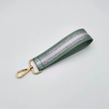 Close-up of green woven handbag strap with silver glitter stripe and gold lobster clasp - Matcha Green