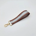 Close-up of woven wrist strap with brown and silver stripes and gold metal hardware - Deep Pink