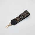 Close-up of ethnic embroidered bag strap with floral pattern and gold metal lobster clasp - Silver Clasp / Light Green Floral On Black