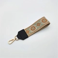 Macro detail of ethnic embroidered bag strap with floral pattern and gold metal clasp - Silver Clasp / Brown Floral On Khaki