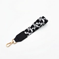 Close-up of cow print wrist strap with black leather detail and golden lobster clasp - Black Cow Print